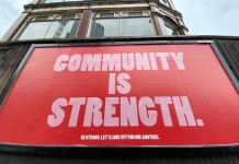 Nell'immagine la scritta su un cartellone pubblicitario che recita "La comunità è la forza" - Smart Marketing