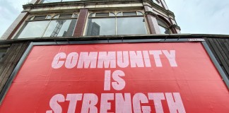 Nell'immagine la scritta su un cartellone pubblicitario che recita "La comunità è la forza" - Smart Marketing