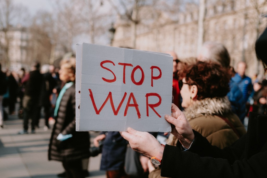 Nell'immagine una donna durante una manifestazione regge un cartello con la scritta "No War" - Smart Marketing