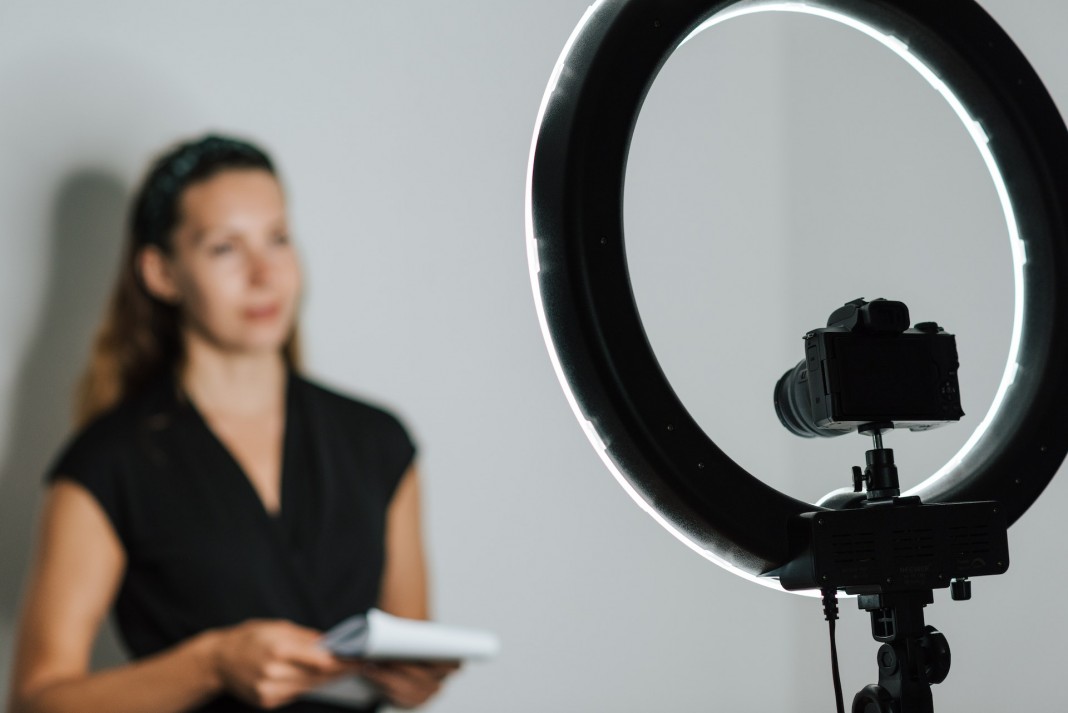 Nell'immagine una ragazza realizza un contenuto video con una fotocamera dotata di ring light - Smart Marketing