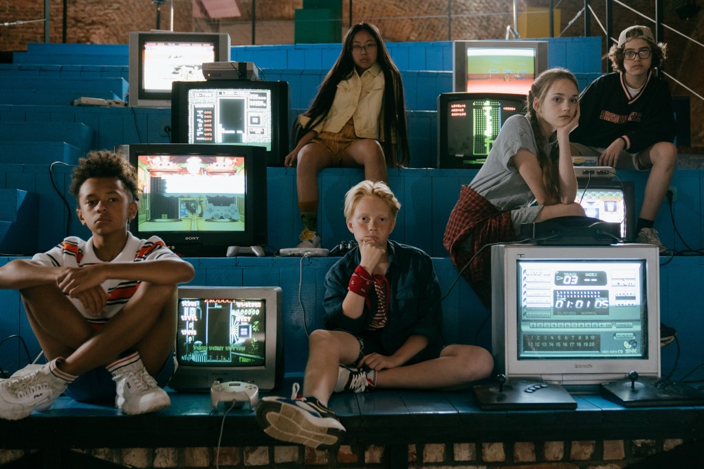 Nell'immagine degli adolescenti seduti fra schermi, TV a tubo catodico e vecchie console di videogame - Smart Marketing