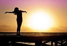 Nella foto una ragazza con le braccia aperte sullo sfondo di un tramonto - Samart Marketing
