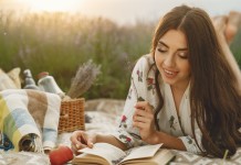 Nell'immagie una ragazza legge un libro durante un picnic sulla spiaggia - Smart Marketing