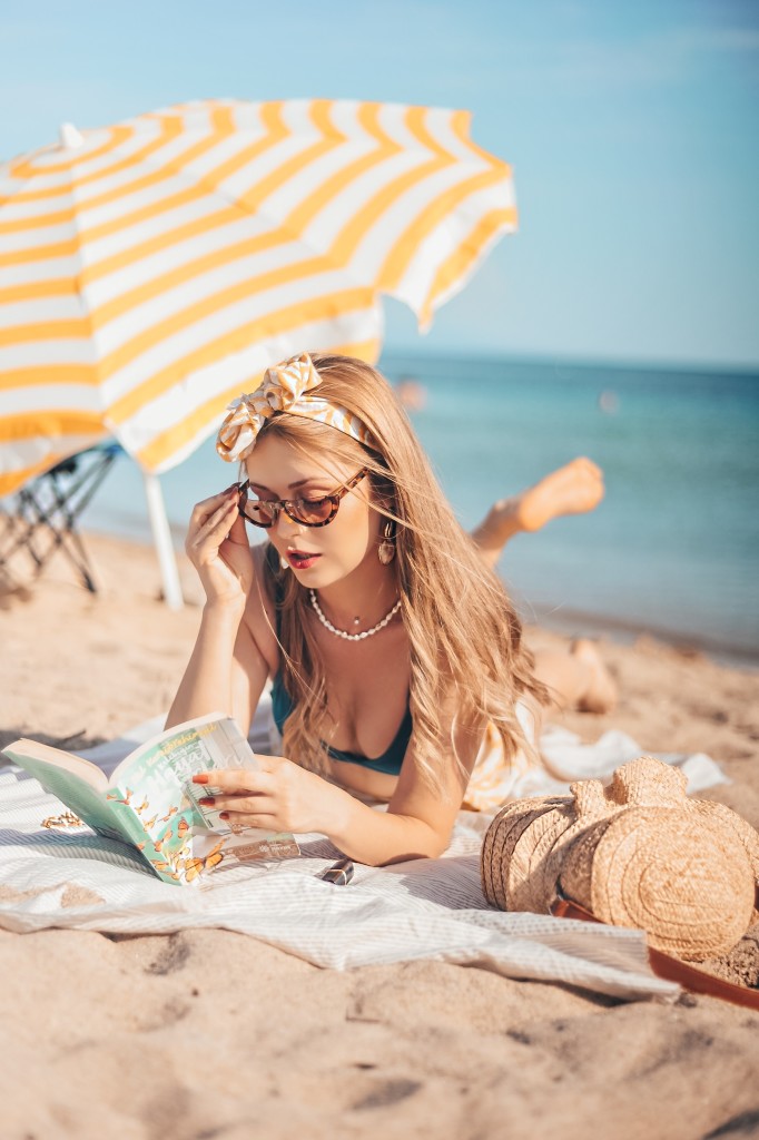Nell'immagine una ragazza legge un libro in spiaggia sotto l'ombrellone - Smart Marketing