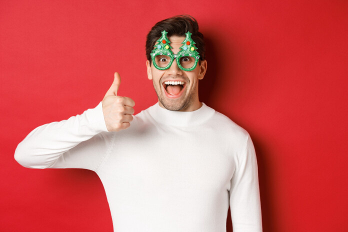 Nell'immagine un ragazzo con degli occhiali a tema natalizio fa i gesto del pollice alzato - Smart Marketing