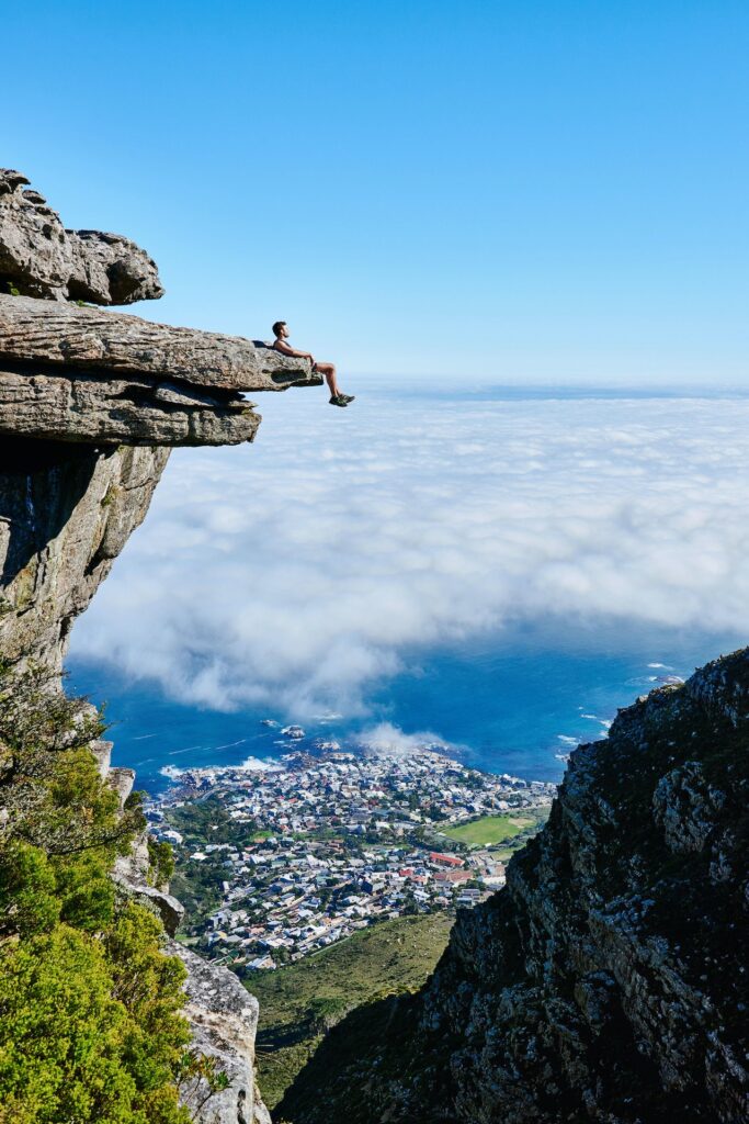 Nell'immagine un ragazzo è seduto su una roccia a strapiombo davnti ad un panorama di montagna - Smart Marketing