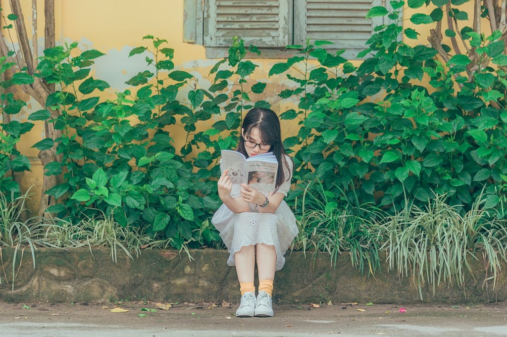 Nell'immagine una ragazzina legge in un giardino - Smart Marketing