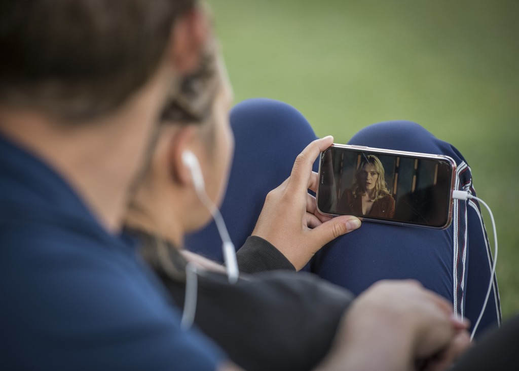 Nell'immagine una ragazza guarda una serie TV sul suo smartphone - Smart Marketing