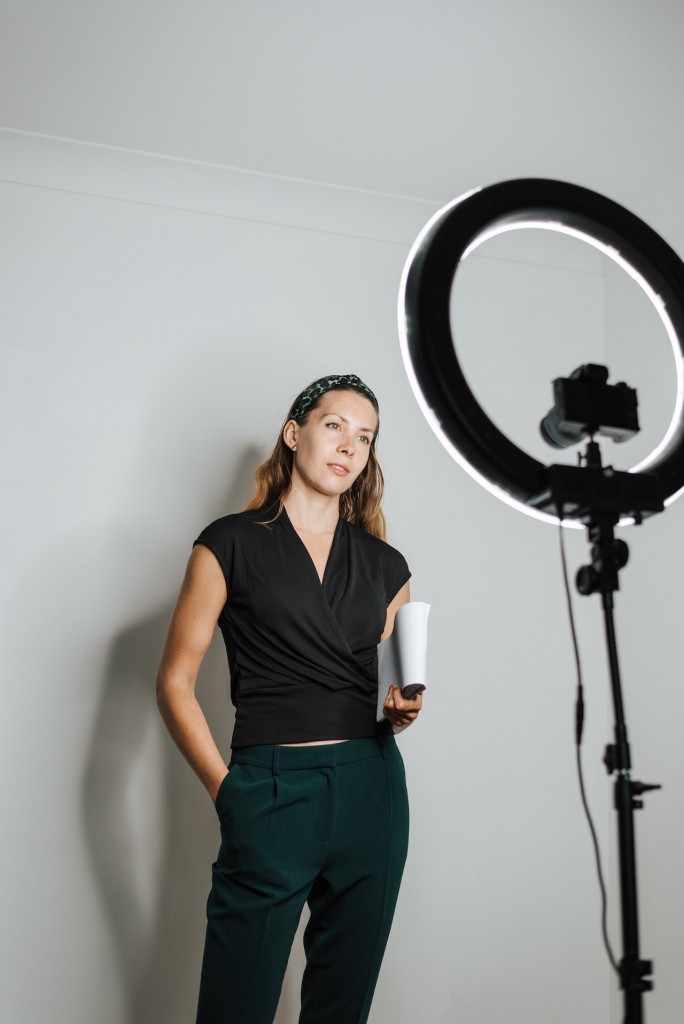 Nell'immagine una ragazza in piedi, con una fotocamera dotata di ring light, sta realizzando un contenuto video - Smart Marketing