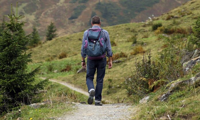 Nell'immagine un ragazzo con zaino in spalla percorre un sentiero di montagna - Smart Marketing