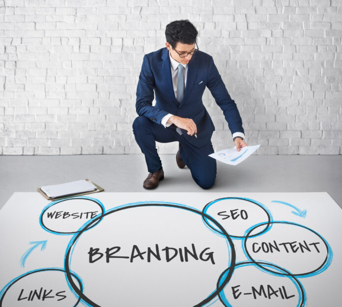Nell'immagine un ragazzo sistema dei fogli sul pavimento dove è scritta la parola Branding - Smart Marketing