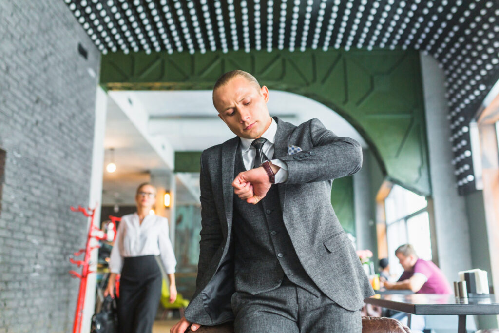Nell'immagine un uomo in giacca e cravatta corre mentre osserva il suo orologio da polso - Smart Marketing
