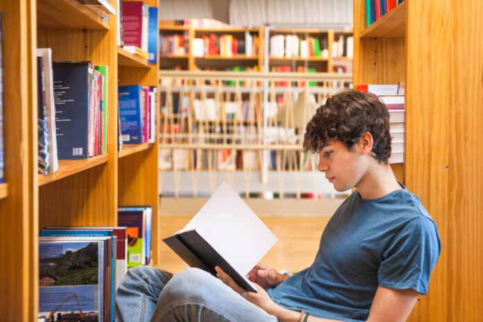 Nell'immagine un ragazzo legge un libro in una libreria - Smart Marketing