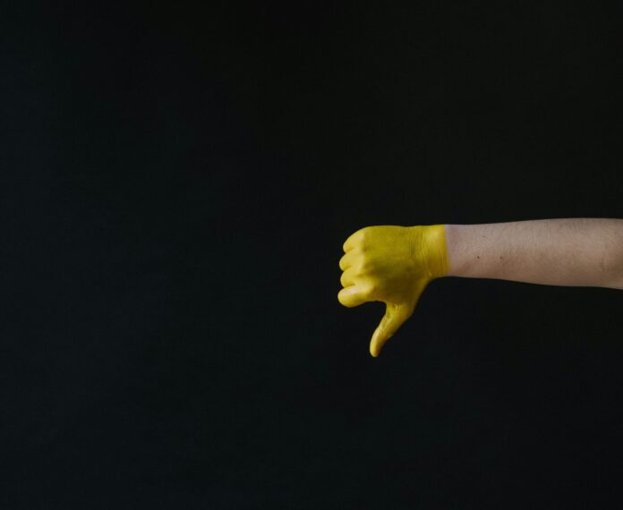 Nell'immagine una mano dipinta di giallo fa il gesto del 
