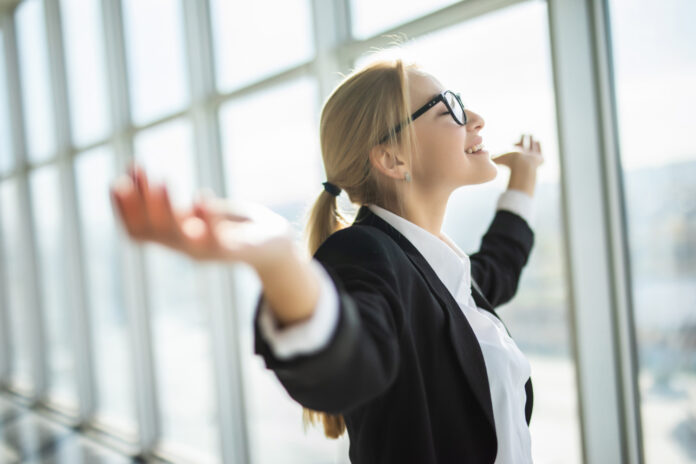 367 Professionista sorridente in ufficio davanti a grandi vetrate, simbolo di cambiamento, nuove opportunità e crescita professionale.